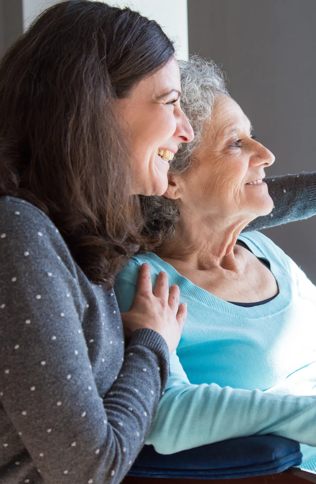 A professional carer sharing a relaxed moment with an older woman at home